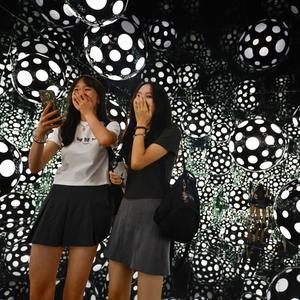 Two girls take selfies inside the art installation âDots Obsession: Aspiring to Heaven's Love' at M+ Visual Culture Museum in Hong Kong. 