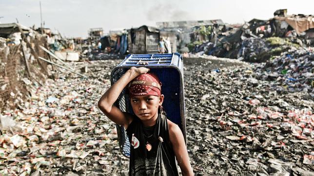 Ein kleiner Junge sammelt Plastikmüll auf den Philippinen.