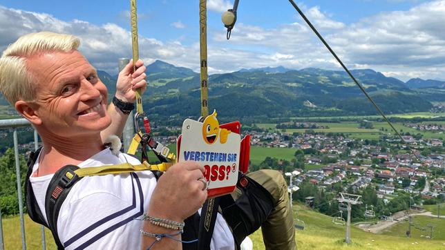 Bild: SWR/Kimmig Entertainment Guido Cantz saust mit über 80km/h nur in einem Stahlseil eingehängt den Oberaudorfer Hausberg hinunter.