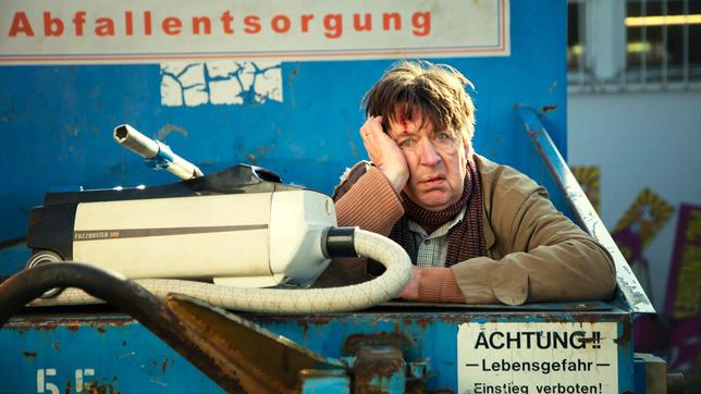 Bild: ARD Degeto/Dennis Pauls Ihm bleibt nichts erspart: Verzweifelt versucht Hubert Lotzmann (Jörg Gudzuhn), „Herrn Neumann“ zu retten, den er versehentlich mit dem Staubsauger aufgesaugt hat.