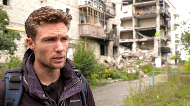 Richard Weir von der unabhängigen Menschenrechtsorganisation Human Rights Watch vor einem zerstörten Wohnblock.