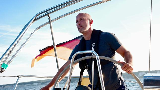 Bild: MDR/Christian Werner Schauspieler und Ostseeliebhaber Benno Fürmann am Steuer eines Segelschiffes auf der Ostsee während der Dreharbeiten zum Film „Ostsee am Limit“.