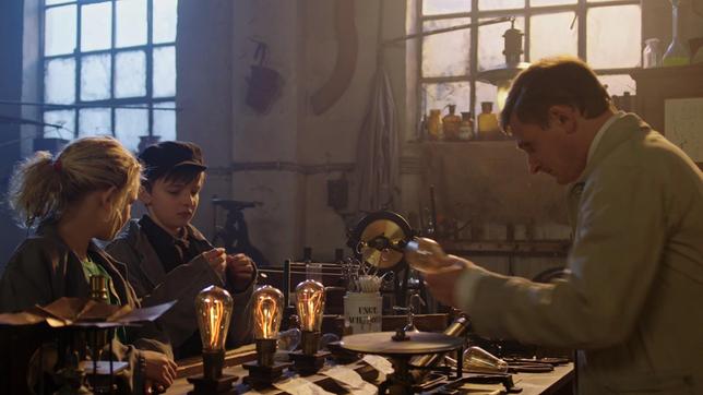 Thomas Alva Edison (Florian Lukas) erklärt Juna (Claire Wegener) und Hugo (Yuri Gayed), wie der Bau einer Glühbirne funktioniert.