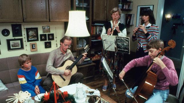 Bild: WDR Vorweihnachtliche Hausmusik bei Familie Beimer in der ersten Folge der Lindenstraße: v.l.: Klausi (Moritz A. Sachs), Vater Hans (Joachim Hermann Luger), Mutter Helga (Marie-Luise Marjan), Tochter Marion (Ina Bleiweiß) und Benny (Christian Kahrmann) (Erstsendedatum: 08.12.1985).