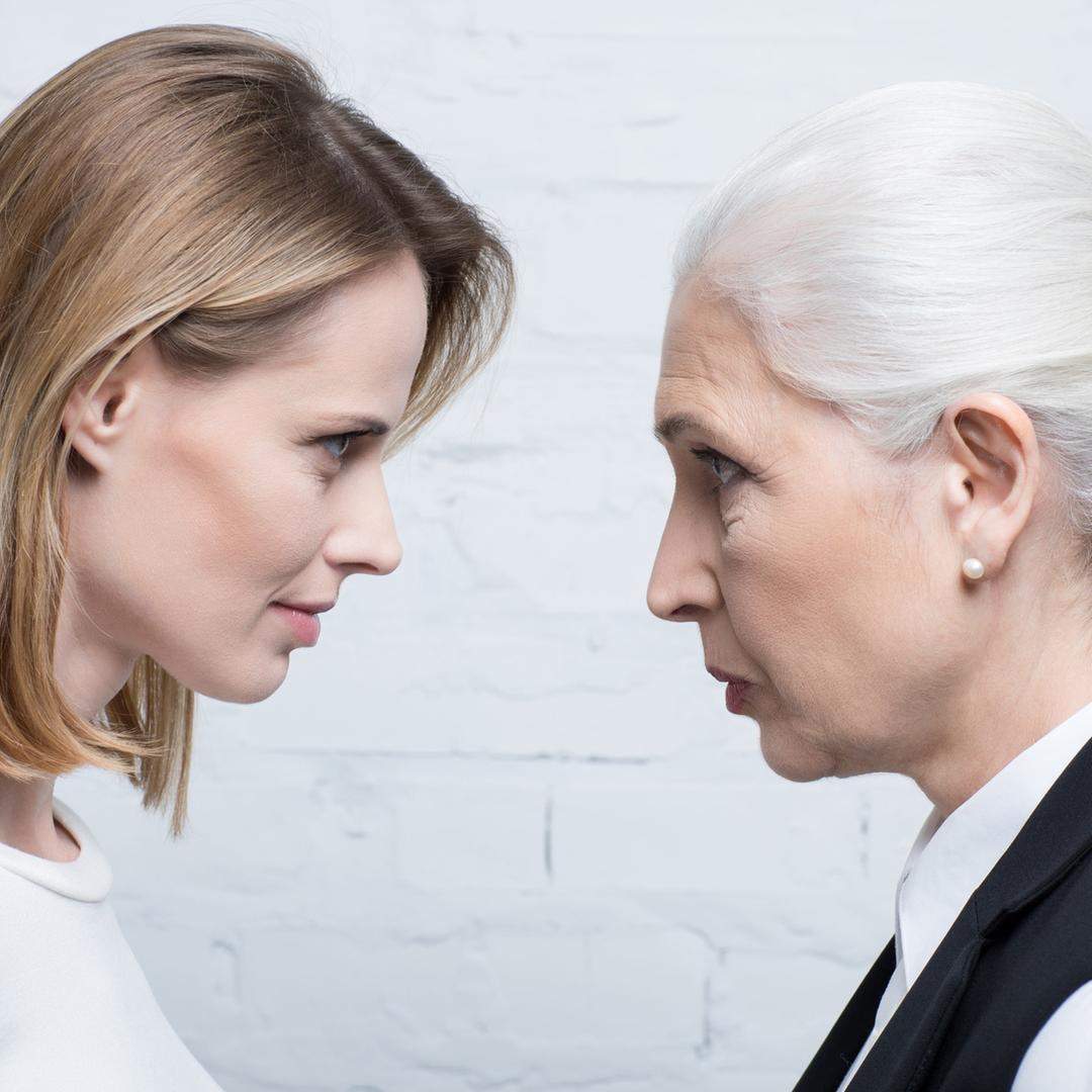 Eine junge und eine alte Frau stehen sich Kopf an Kopf gegenüber