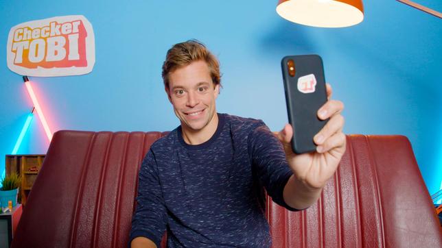 Bild: BR Checker Tobi mit seinem Handy in der Checker-Bude.