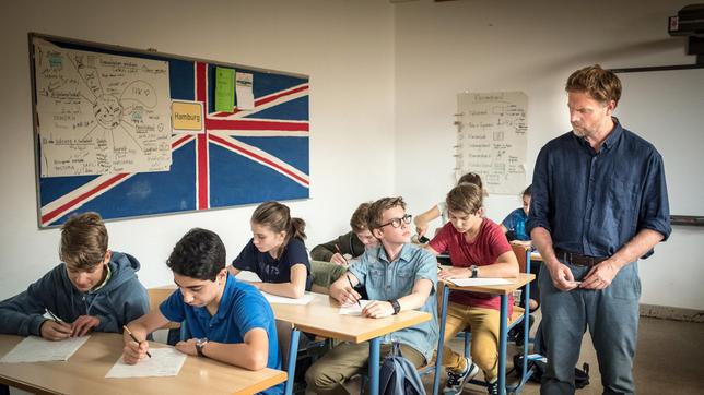 Benny (Ruben Storck, Mitte) hat große Probleme mit der Englischarbeit, die sein Lehrer Martin Schulze (Janek Rieke) ausgeteilt hat.