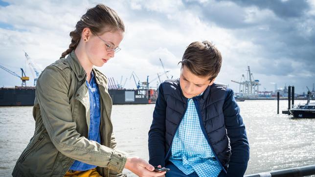 Bild: NDR/Boris Laewen Pinja (Sina Michel, li.) und Ramin (Jann Piet, re.) kriegen eine wichtige Nachricht per SMS.