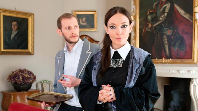 Bild: BR/Tresor TV Produktions GmbH/Claudia Hofmair Vincent (Benjamin Holtschke) und Silvana (Mascha Müller) stehen im Kaminzimmer. Sie frohlockt, dass Pia ihrem Zaubertrank nicht gewachsen sein wird.