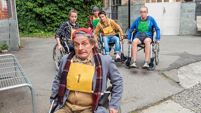 Bild: SWR/Patricia Neligan Charlotte, Meike und Niklas bekommen beim Rolli- Basketball mit Motzgurkes Neffen Leo selbst den griesgrämigen Hausmeister Griesgrämer (Volker Zack Michalowski) zum Sporttreiben.