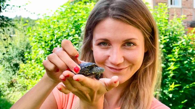 Jana hält eine zwei Jahre alte Europäische Sumpfschildkröte auf der Hand.