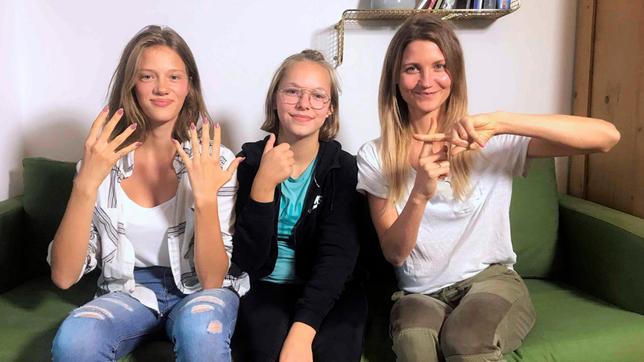 Bild: WDR Jana sitzt mit der tauben Navina und ihrer Freundin Luana auf einer Couch. So sieht „neuneinhalb“ in Gebärdensprache aus.
