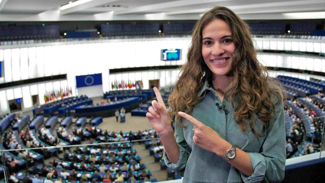 Moderatorin Mona steht auf der Empore des Straßburger Europaparlaments, hinter ihr der mit Schüler*innen besetzten Plenarsaal. Die Schüler*innen kommen aus allen EU-Mitgliedstaaten und verbringen im Rahmen des Projekts „Euroscola“ einen Tag als Abgeordnete.
