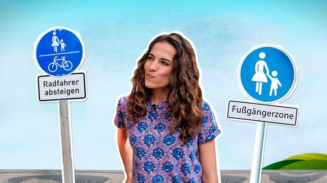 Bild: WDR Mona steht grübelnd vor den Verkehrsschildern mit den Aufschriften „Radfahrer absteigen“ und „Fußgängerzone“.