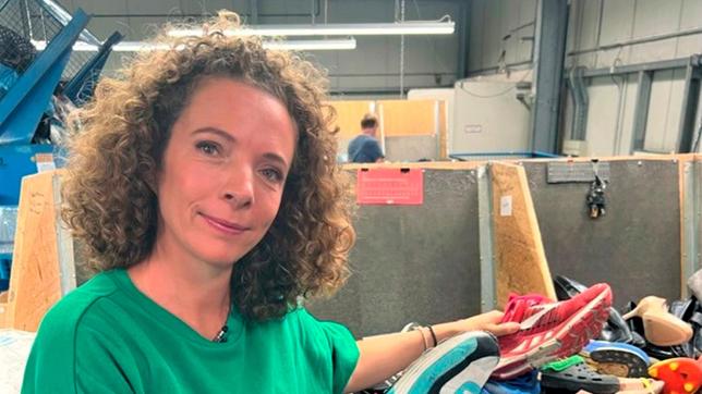 Bild: WDR Reporterin Gesa steht in einem Textilsortierunternehmen vor der Schuhsortierung mit zwei Sneakern in der Hand.