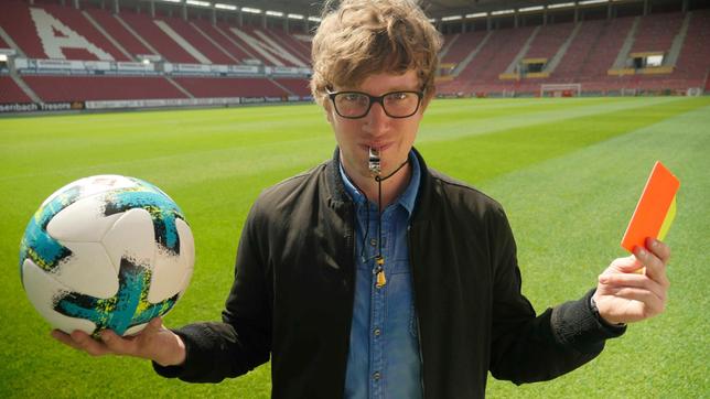 Bild: WDR/tvision Robert mit Trillerpfeife, Fußball und Schiedsrichterkarten auf dem Spielfeld des Bundesligisten Mainz 05.
