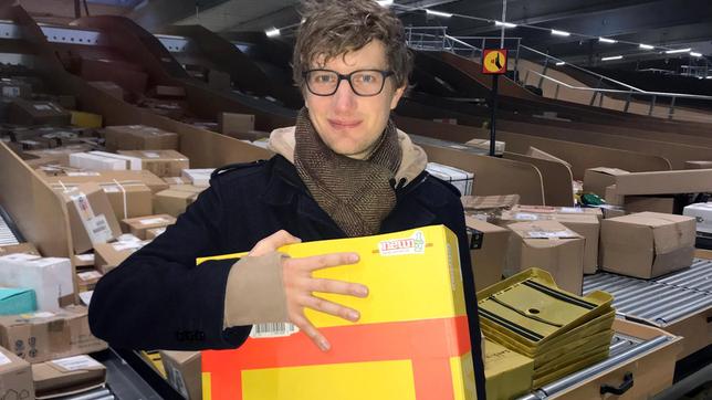 Bild: WDR/tvision Robert steht mit einem Paket in einem Paketverteilzentrum.