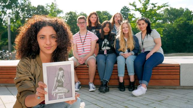 Bild: WDR/tvision Siham mit einem eingerahmtem Ariana Grande-Autogramm und einigen deutschen Ariana Grande-Fans