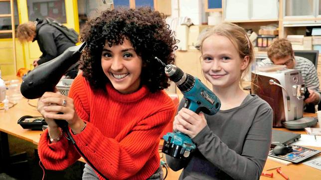 Bild: WDR Siham (l) und Ella im Repair Café. Die beiden halten einen reparierten Fön und eine Bohrmaschine in die Kamera.