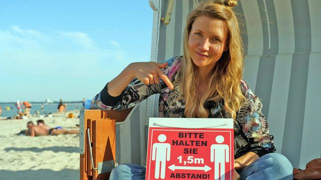 Jana in einer Strandmuschel mit einem Schild in der Hand