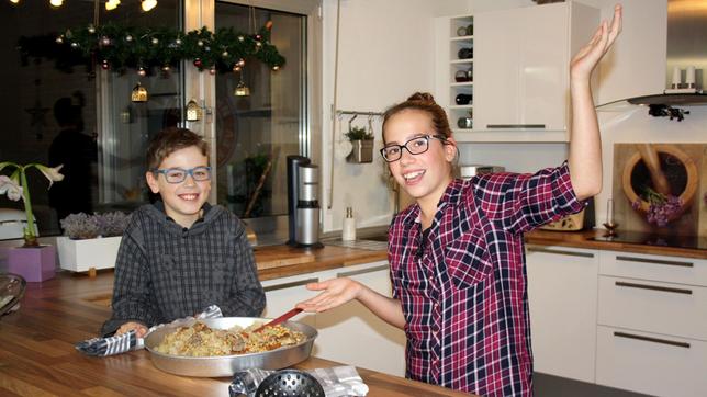 Bild: SWR/Nordisch Filmproduktion/Jennifer Beisker Maya (rechts) und Lukas (links) sind beste Freunde. Am liebsten fahren sie mit dem Kettcar um die Wette oder drehen eigene Actionfilme. Actionreich wird es mit den beiden auch in der Küche! Denn die zwei Köche müssen es mit einem störrischen Blumenkohl und glitschigen Hähnchenkeulen aufnehmen. Und dann fallen ihnen auch noch die frisch geschälten Kartoffeln auf den Boden. Mayas libanesisches Gericht Maloubi sorgt also für mächtig Trubel. Ob es den Gästen am Ende trotzdem schmecken wird?