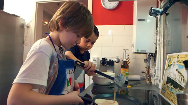 Bild: SWR/Nordisch Filmproduktion Nino (re.) ist acht Jahre alt und hat richtig viele Hobbies: Er spielt Gitarre, liebt Fußball und schwimmt gerne. Ninos Papa kommt aus Frankreich und deshalb will Nino bei "Schmecksplosion" für seine Freunde etwas typisch Französisches kochen: Es gibt Crêpes mit heißer Schokolade. Sein bester Freund Nik hilft ihm dabei.