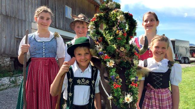Bild: WDR/Malin Büttner In den Ferien helfen Kinder aus der Nähe auf der Alpe. Hannes (vorne links), Magdalena (vorne rechts) und Jona (Mitte hinten) und zwei Helferinnen stehen neben der geschmückten Kuh „Lena“.