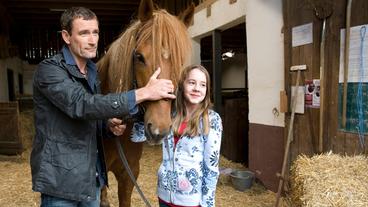 Bild: SWR/Maria Wiesler Tierarzt Dr. Philipp Hansen (Heikko Deutschmann) und Tochter Greta (Enya Elstner) haben das Pflegepferd Windrose verarztet.