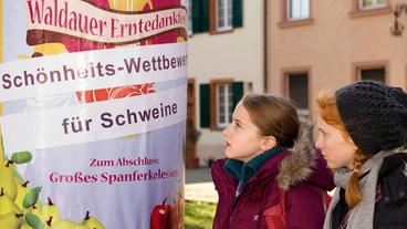 Bild: SWR/Maria Wiesler Greta (Enya Elster, links) und Celine (Zora Achtnich, rechts) erfahren von der besonderen Überraschung: dem Schönheitswettbewerb für Schweine anlässlich des Erntedankfestes Waldau.