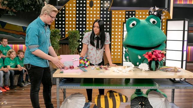 Bild: SWR/Sabine Stumpp Der Origami Virtuose Christian Saile, gibt unserer Moderatorin Jessica Schöne einen kleinen Einblick in die Welt des Papier faltens - Günter Kastenfrosch gefallen besonders die bunten Blumen.
