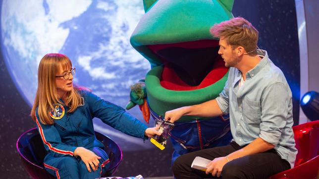 Bild: SWR/Markus Palmer Die studierte Meteorologin und angehende Astronautin Dr. Insa Thiele-Eich, lässt hier unseren Moderator Johannes Zenglein von der spezeillen - gefriergetrockneten Nahrung der Astronauten probieren. Das kann doch nicht schmecken, denkt sich Günter Kastenfrosch und bringt schnell ein paar frische Karotten für die Astronautin.