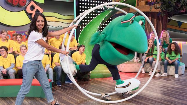 Bild: SWR/Sabine Stumpp Frosch Günter versucht sich am Rhönrad. Moderatorin Mushda Sherzada hilft ihm.
