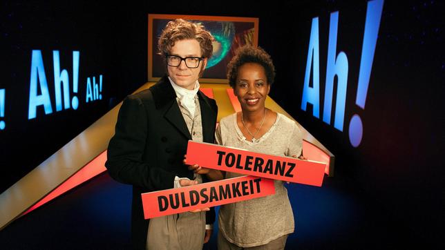 Bild: WDR/Thorsten Schneider Heute geht es bei "Wissen macht Ah!" um die wirklich wichtigen Themen: Shary und Mr. Darcy alias Ralph klären, was die Begriffe Toleranz und Integration eigentlich bedeuten und warum es okay ist, ein Kostüm aus dem 19. Jahrhundert zu tragen oder eben nicht. Sie unterscheiden lebendige von toten Sprachen und räumen mit Vorurteilen darüber auf, was eigentlich „deutsch“ ist.