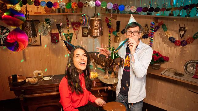 Clarissa und Ralph sitzen mit Partyhüten im dekorierten Partykeller