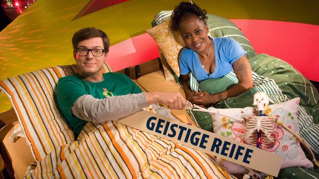 Ralph und Shary liegen in einem Bett mit einem Schriftzug "Geistige Reife"