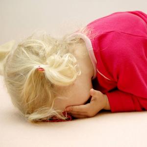 Kleines Mädchen liegt weinend auf dem Boden. Traumatische Erlebnisse können sich massiv auf Seele und Körper auswirken. Wissenschaftler erforschen unter anderem, wie sich traumatisierte Kinder entwickeln.