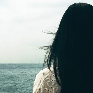 Eine Frau steht einsam vor dem Meer