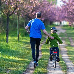 Ein Jogger mit einem Kind auf dem Fahrrad.