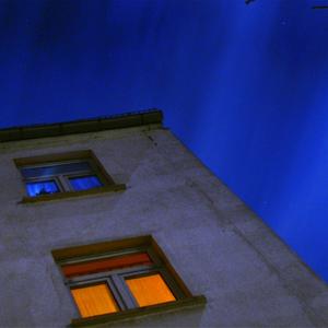 Eine Hausecke mit beleuchteten Fenstern in der Nacht