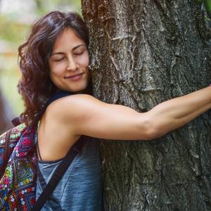 Eine junge Frau umarmt einen Baum