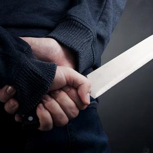 Mann hält Messer hinter dem Rücken