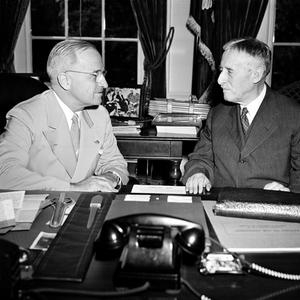 US-Präsident Harry Truman (linkts) nach seiner Rückkehr von der Potsdamer Konferenz an seinem Schreibtisch im Weißen Haus mit Kriegsminister Henry L. Stimson. Die Männer diskutieren über die Atombombe, die auf die japanische Stadt Hiroshima abgeworfe