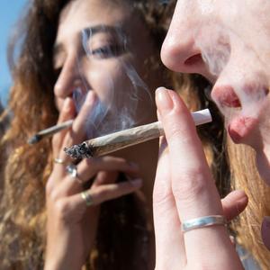 Junge Frauen rauchen bei einer Protestaktion für legalen Cannabis-Konsum einen Joint