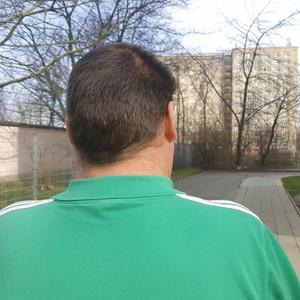 Ein Mann im grünen Shirt von hinten.