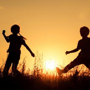 Drei Kinder spielen fröhlich im Sonnenuntergang.