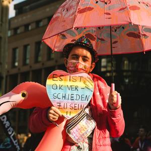 Ein Mensch hält ein Schild auf dem steht: Es ist okay verschieden zu sein auf der Pride Parade in Düsseldorf, 2021