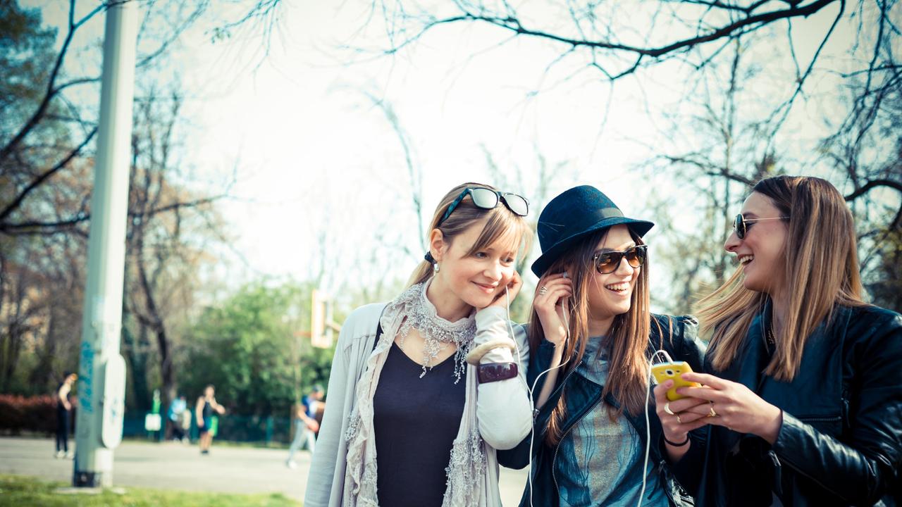 drei junge Frauen hören Musik mit Smartphone
