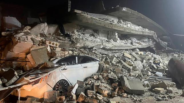 Ein Auto ist unter den Trümmern eines eingestürzten Gebäudes in der Stadt Azmarin in der nordsyrischen Provinz Idlib zu sehen. Zwei heftige Erdbeben haben kurz nacheinander am frühen Montagmorgen (06.02.2023) den Südosten der Türkei und Syrien erschüttert. 