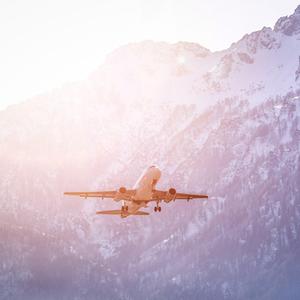 Ein Flugzeug hebt vor einem Schneebedecktem Bergmassiv ab.