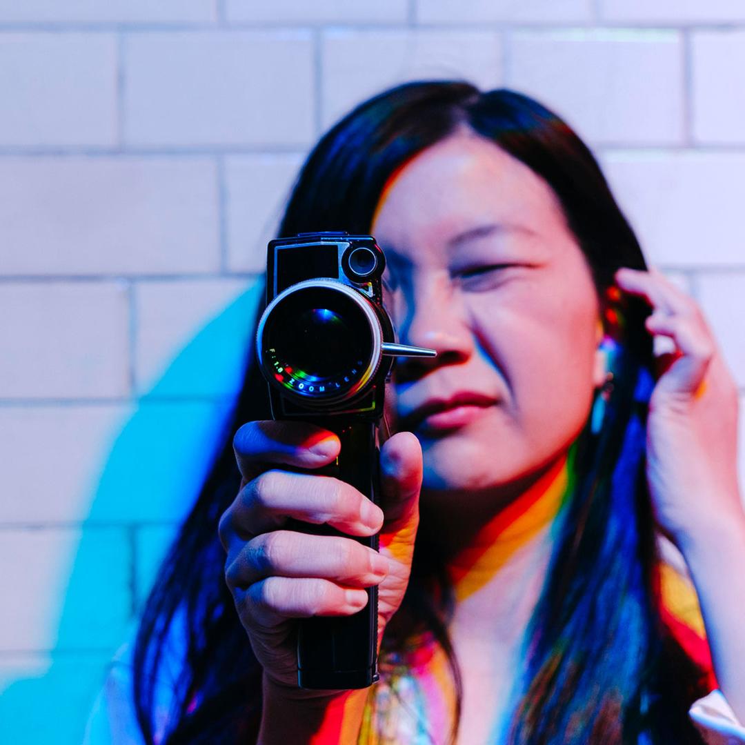 Frau schaut durch eine Filmkamera und kneift eine Auge dabei zu.・Bild: picture alliance Frau schaut durch eine Filmkamera und kneift eine Auge dabei zu.